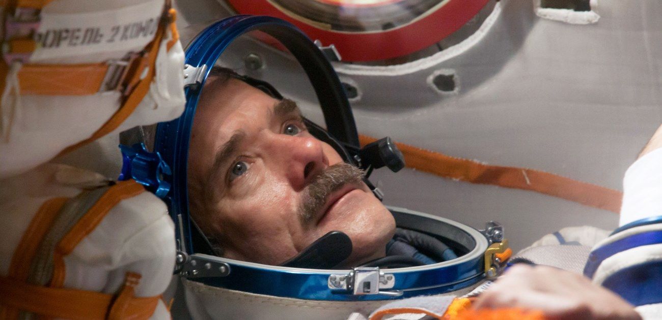 Astronaut in space capsule wearing a vibrant helmet, gazing thoughtfully upward, ready for space mission.