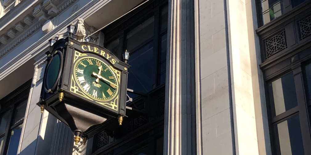 Vintage Clerys clock on a historic city building facade under clear blue sky.