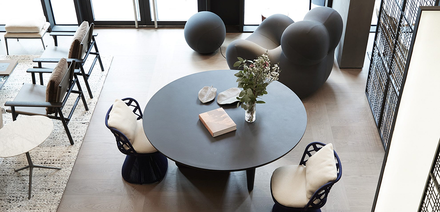 Modern living room with round table, two chairs, stylish armchair, and decor in a minimalist setting.