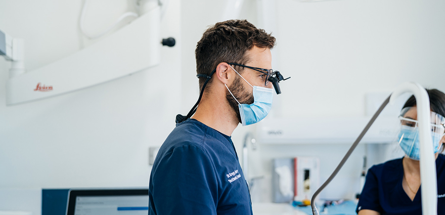Dentist wearing magnifying loupes and mask working in a dental clinic.