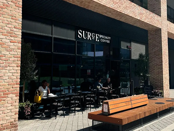 Exterior view of Surge Specialty Coffee shop with outdoor seating and modern brick facade.