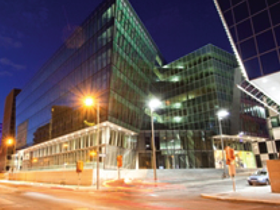 Modern glass office building illuminated at night with street lights, showcasing architectural design and city ambiance.