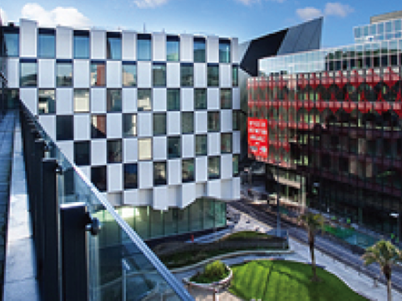 Modern urban architecture with checkered building facade and glass structures under a clear sky.