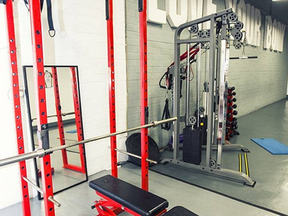 Gym with red weightlifting equipment, mirrors, and cable machine for strength training exercises.