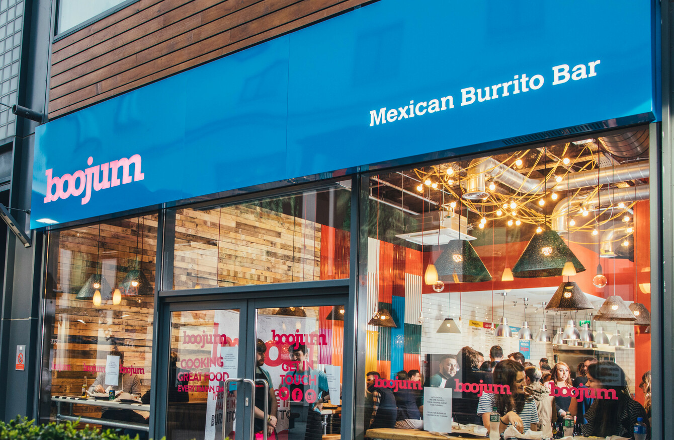 Mexican Burrito Bar storefront with people inside, featuring modern decor and wooden accents.
