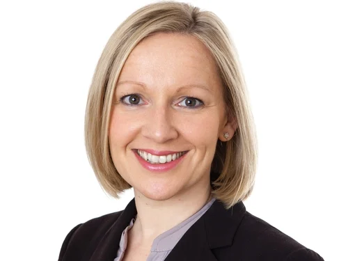 A professional woman smiling in a business suit on a white background.