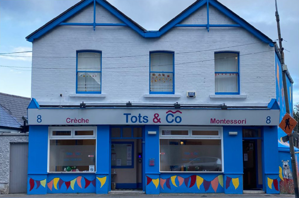 Brightly colored Tots & Co Montessori crèche building with blue accents and painted murals on the exterior.