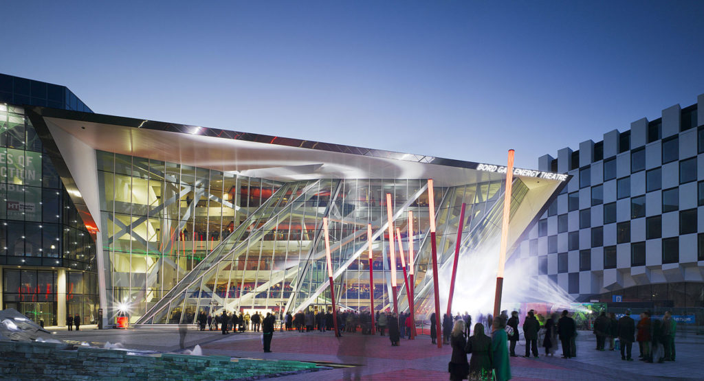 Modern architecture of Bord Gáis Energy Theatre in Dublin at twilight with crowds gathered outside.