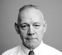 Black and white portrait of a serious elderly man in a white shirt and tie, looking directly at the camera.